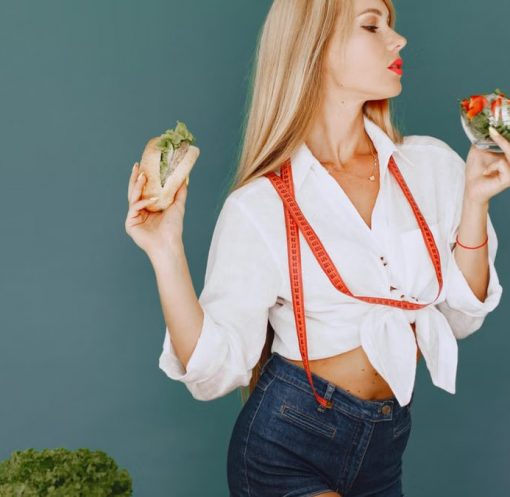 Woman enjoys healthy lifestyle with fresh salad and sandwich, promoting balanced eating.