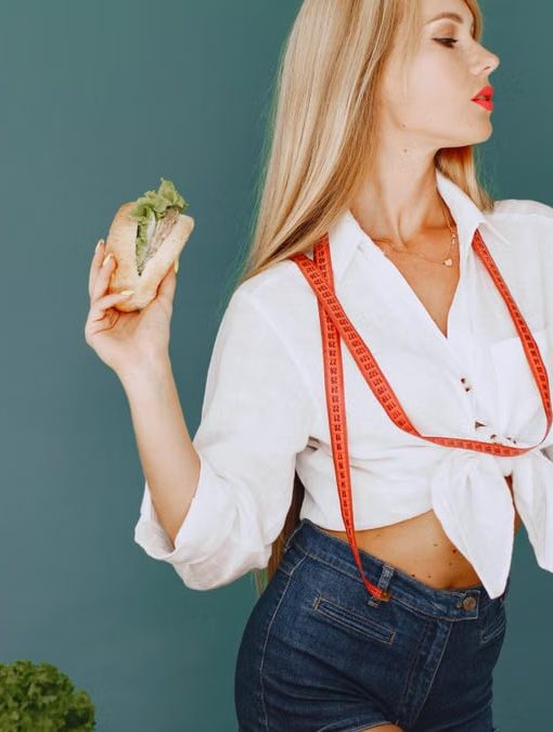Woman enjoys healthy lifestyle with fresh salad and sandwich, promoting balanced eating.