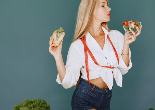 Woman enjoys healthy lifestyle with fresh salad and sandwich, promoting balanced eating.