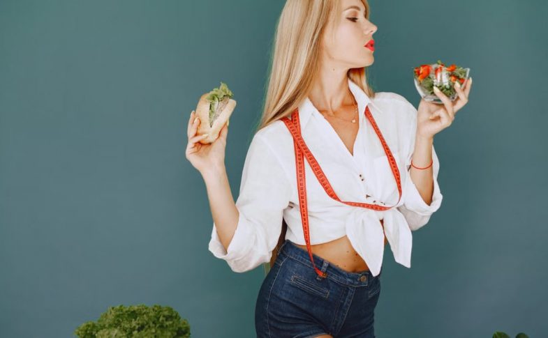 Woman enjoys healthy lifestyle with fresh salad and sandwich, promoting balanced eating.