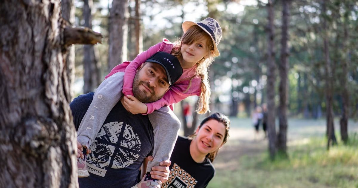 A joyful family enjoying a playful day in a sunlit forest park, capturing the essence of togetherness.